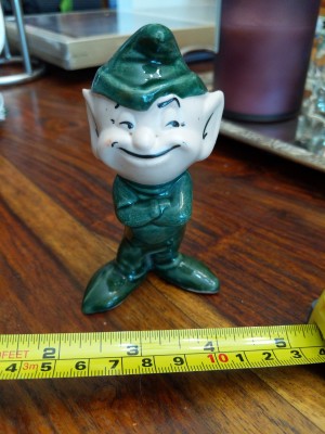 A ceramic elf figurine dressed in green.