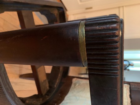 The carved arm of a wooden chair.