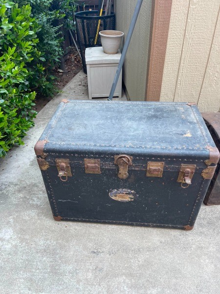 An old dark colored steamer trunk.