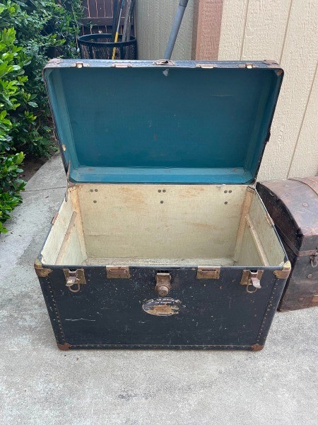 An open dark colored steamer trunk.