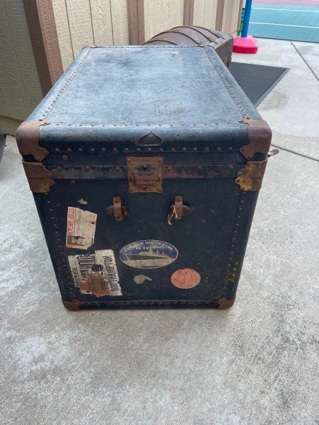 An old dark colored steamer trunk.