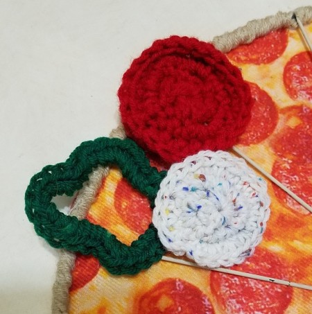 Crocheting vegetables to add to the pizza hanging.