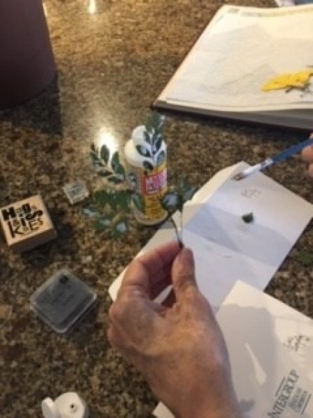 Glueing the greenery to attach to the card.