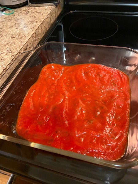 A pan with tomato sauce in the bottom.