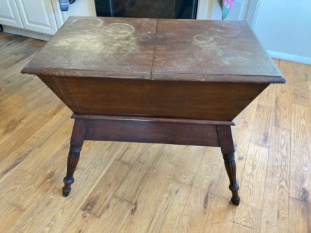 A vintage wooden table with storage underneath.