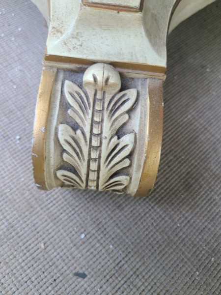 A carved foot of a pedestal dining table.