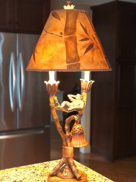 A lamp that has a monkey under the shade.