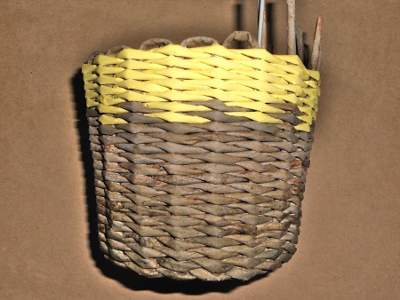 The woven basket with a yellow painted top.