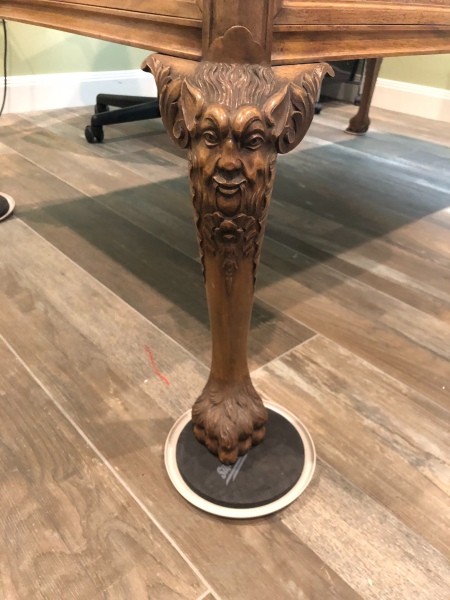 The carved legs of an antique wooden desk.