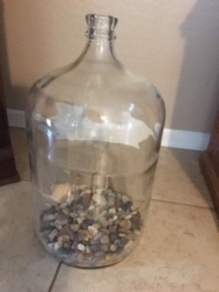 Gravel placed inside a five gallon jug.