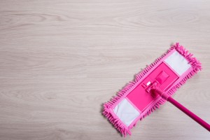 A pink dust mop on a hardwood floor.