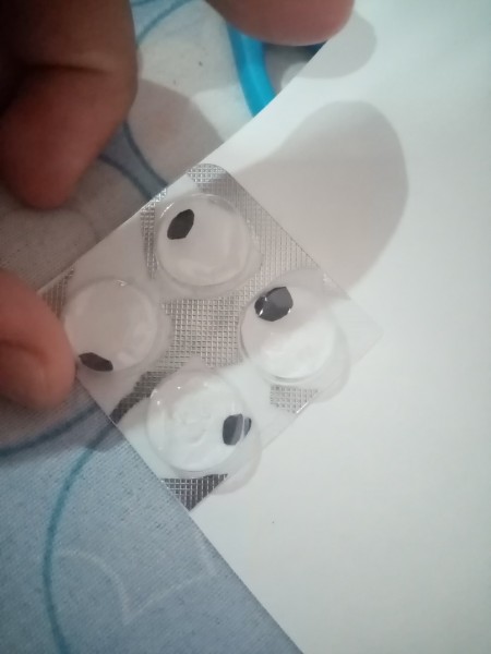 Gluing white paper to the back of the blister pack.