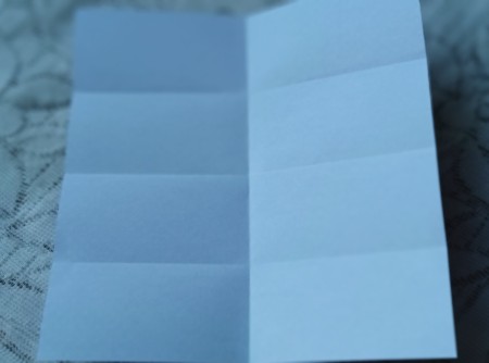Unfolding the paper to see the fold lines.