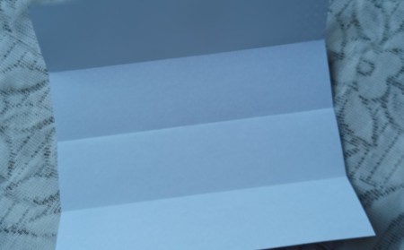 Unfolding the paper to see the fold lines.