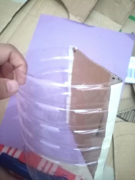 Adding the cardboard to the cut side of the bottle.
