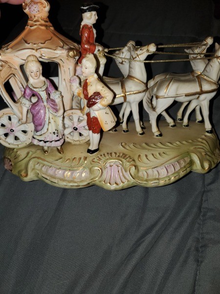 A figurine of a coach with fancy people emerging.