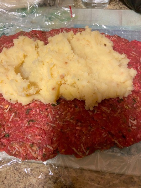 Adding mashed potatoes to the meatloaf.