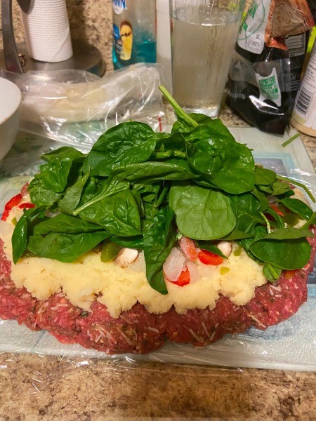 Adding spinach to the top of the meatloaf.