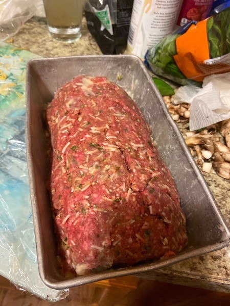 Putting the rolled stuffed meatloaf in a