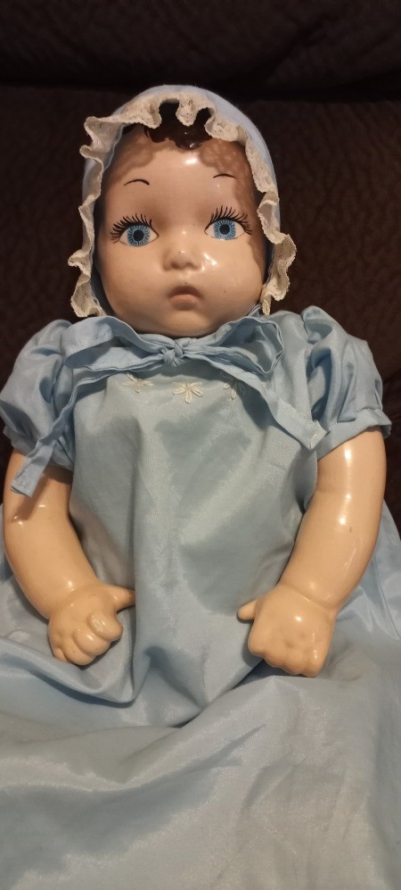 A baby doll in a bonnet and blue dress.