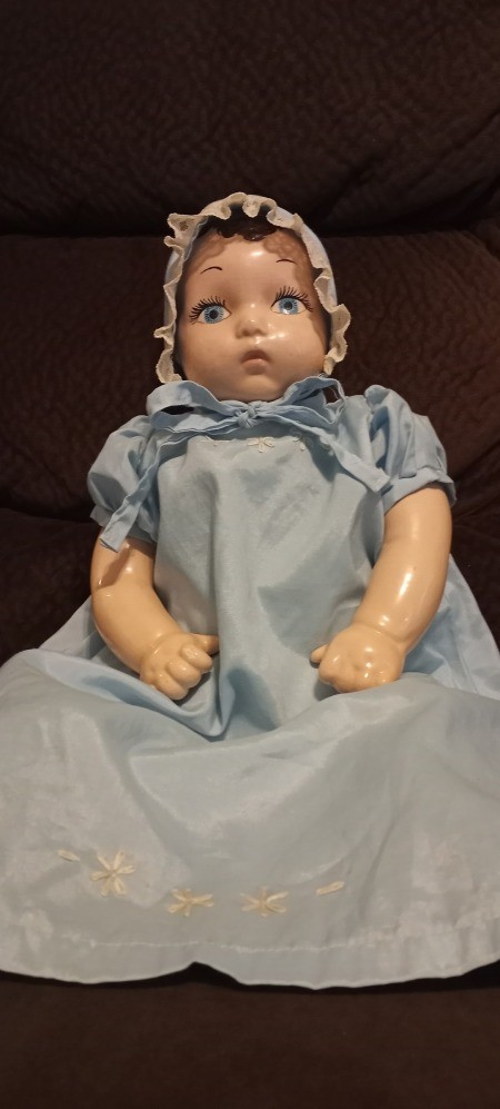 A baby doll in a bonnet and blue dress.
