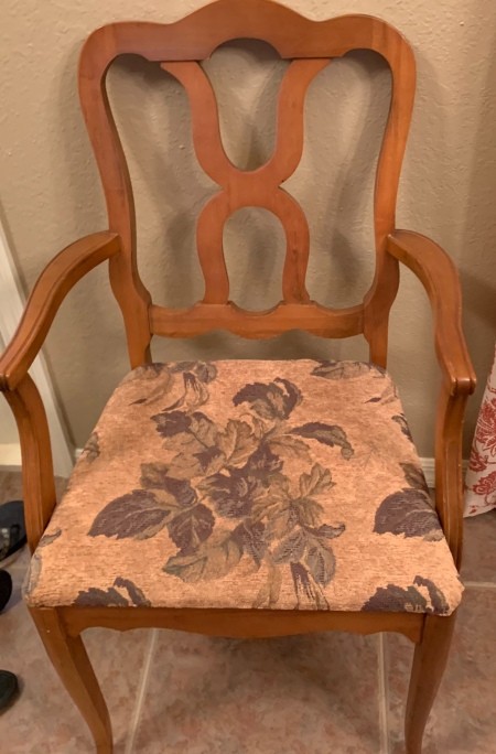 A wooden chair with a covered fabric seat.