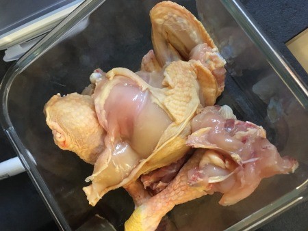 Cut up chicken parts in a glass pan.