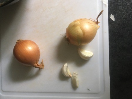 Onions and garlic on a cutting board.