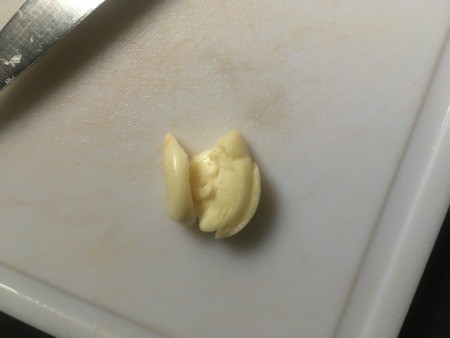 Mincing garlic on a cutting board.