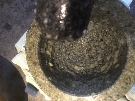 Using a mortar and pestle to make aioli.