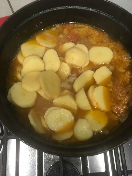 Adding potatoes to the mixture.