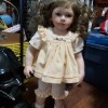 A young girl porcelain doll with light brown hair.