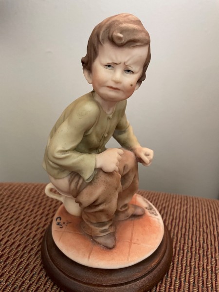 A figurine of a boy on a chamberpot.