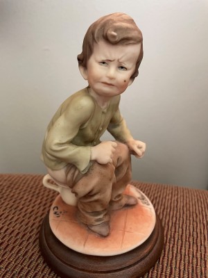 A figurine of a boy on a chamberpot.