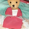 A stuffed teddy bear wearing a red dress.