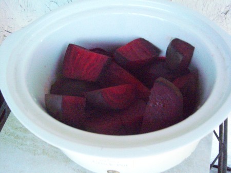 The cut up beets in a slow cooker.