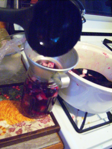 Ladling the beets into a canning jar.