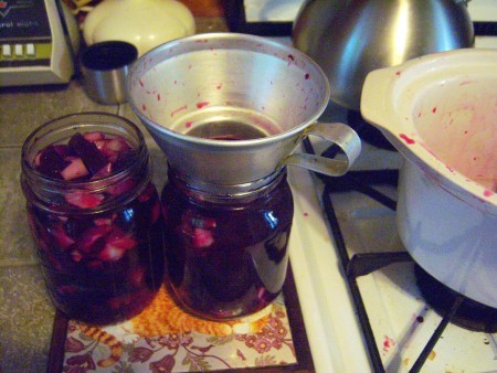 A funnel on top of the beets in a canning jar.