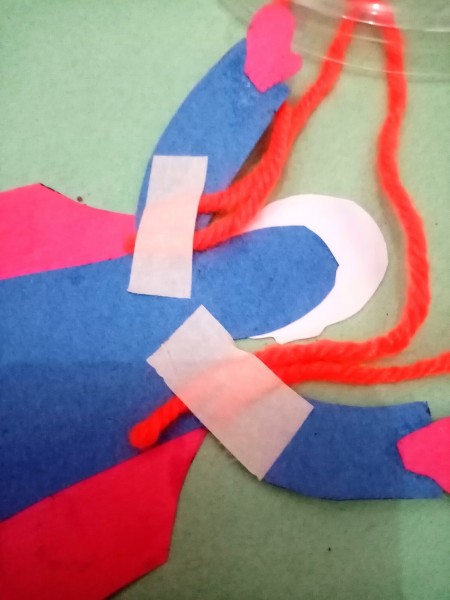 Attaching the yarn strings to the back of the paper figure.