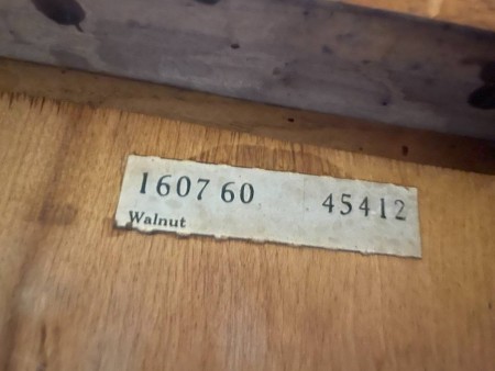 A serial number on the back of a wooden desk.