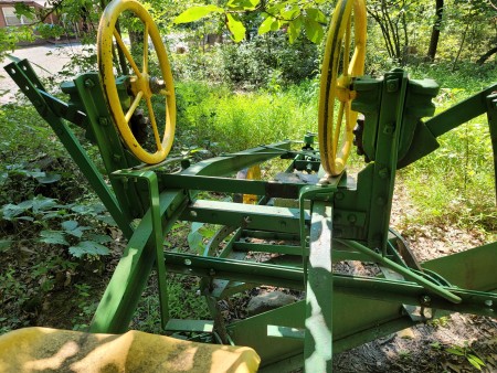 An old fashioned green and yellow grader.