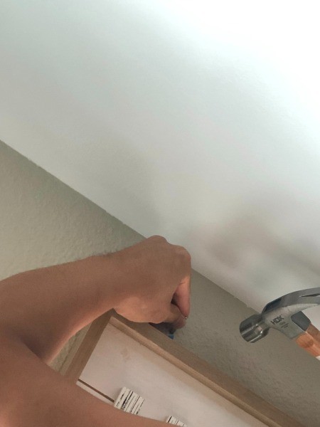 Putting a nail into the wall to hang a picture frame.
