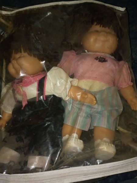 Two Cabbage Patch dolls in a bag.