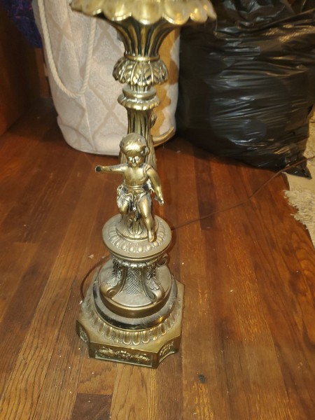 A brass cherub on the base of a lamp.