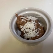 A container of pudding with coconut on top.