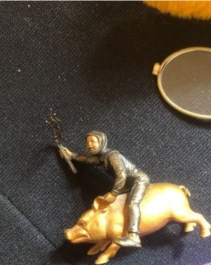 A figurine of a man riding a golden pig.