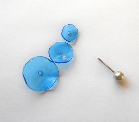 Three circles with holes in the middle next to a stud earring.