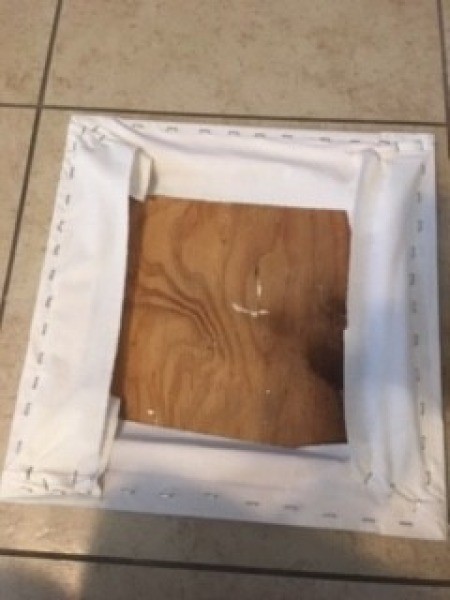 Stapling the folded fabric to the back of the board.