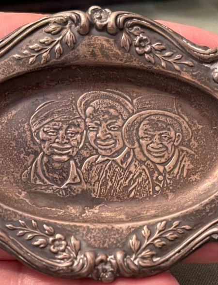 Three faces engraved on a small silver tray.