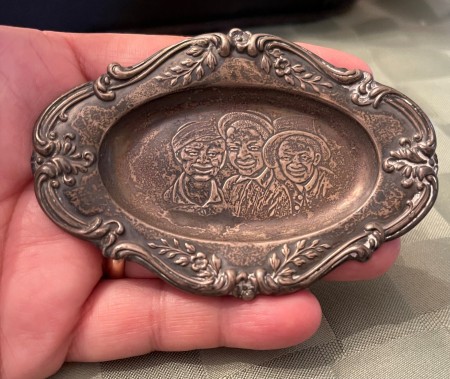 Three faces engraved on a small silver tray.